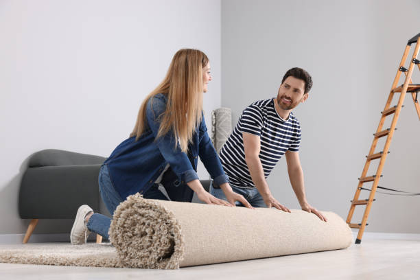 istock Smiling couple unrolling new carpet in room 1707082786