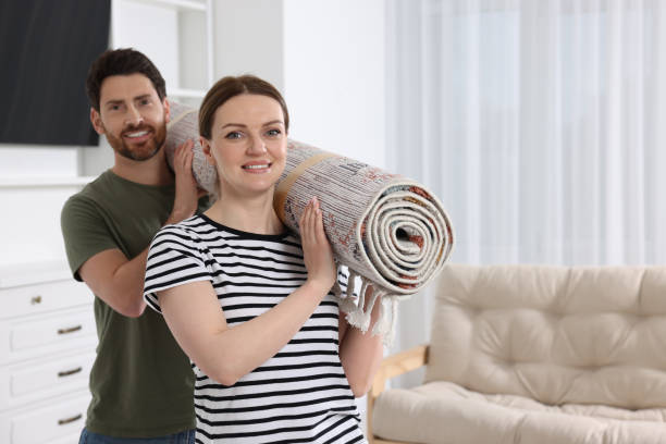 istock Smiling couple holding rolled carpet in room, space for text 1707082795