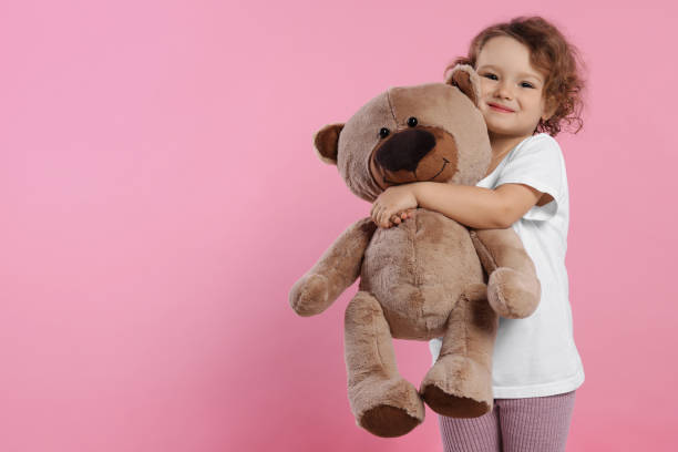 istock Cute little girl with teddy bear on pink background, space for text 1707088178