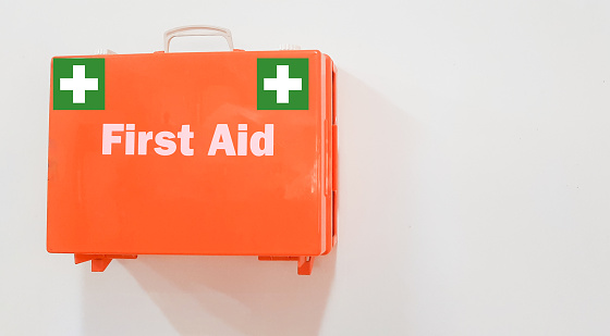 First aid kit orange box on wall at office isolated on white background with copy space for text.