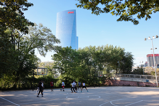Philadelphia, Pennsylvania, USA - Sep 2, 2023: Street ballers playing basketball at a basketball court in Schuylkill River Park with skyscrapers in the background