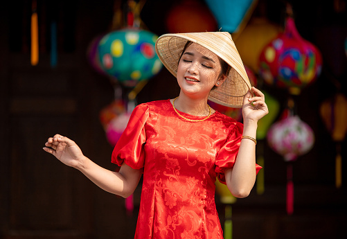 Vietnamese girl with conical hat and modern ao dai, background are Tet lanterns