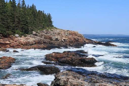 A beautiful coastal landscape with a rocky shoreline and ocean waves in Acadia National Park