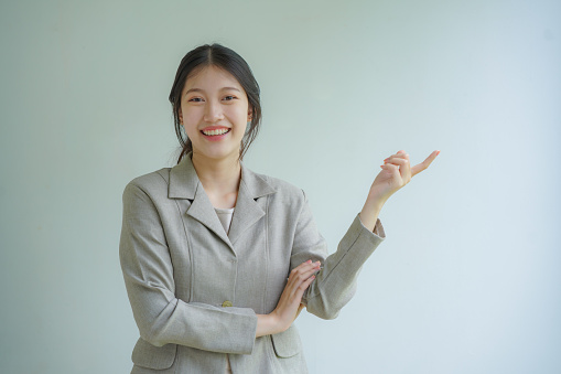 Portrait of a beautiful businesswoman looking at the camera pointing at copy space on a white background.