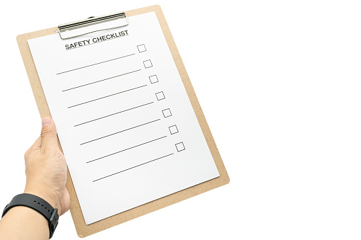 Hand holding Blank checklist paper during safety audit and risk verification for text. Empty safety checklist form isolated on white background.