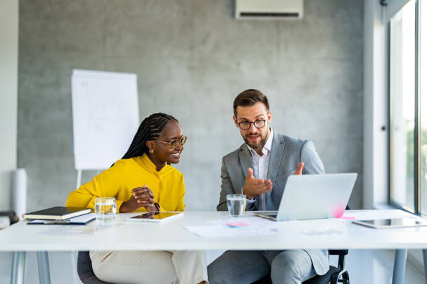 istock Two diverse businesspeople chatting sitting behind laptop in office 1707284048