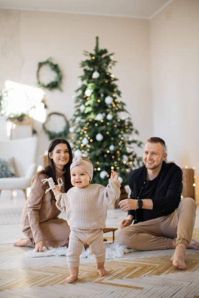 Parents near Christmas tree looking at first daughter steps