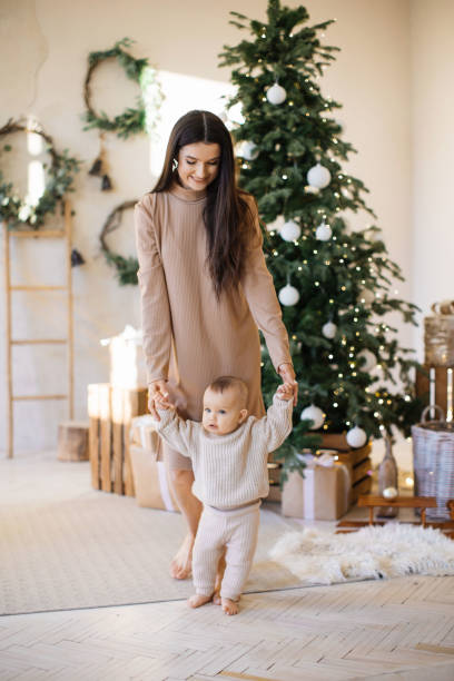 istock Mom teaching baby to make first steps near Christmas tree 1707304625
