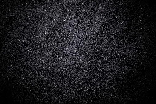 Overhead shot of black sand wave pattern texture background.