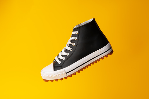 New black and white canvas sneakers on yellow studio background