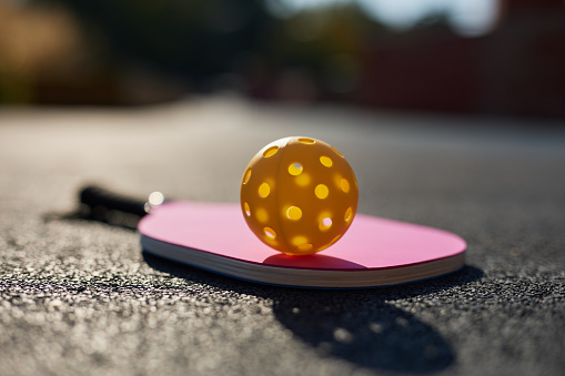 Racket for pickle ball on the court ground. Perforated hollow ball and raquet for pickleball