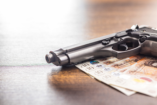 Handgun and  british pound sterling on the wooden table.