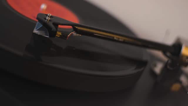 A vinyl record spins in the gramophone music player and plays an old disco. Close-up shot of modern custom vinyl turntable player with carbon tonearm