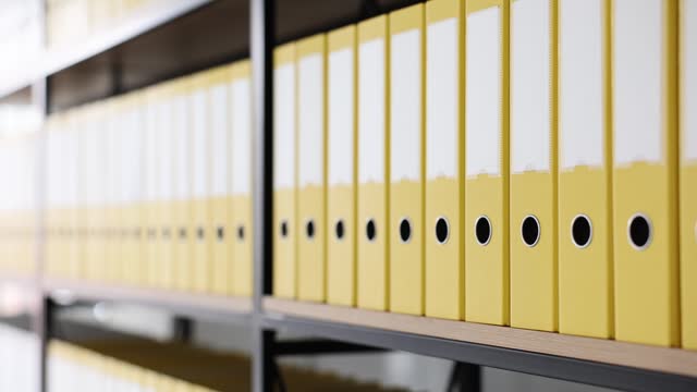 Yellow folders with folders and documents on shelves.