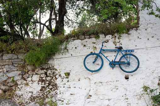 Old blue bicycle hanging on white wall