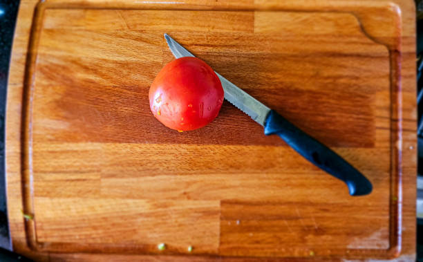 istock Red Tomato on Wooden Cutting Board with knife 1707467726