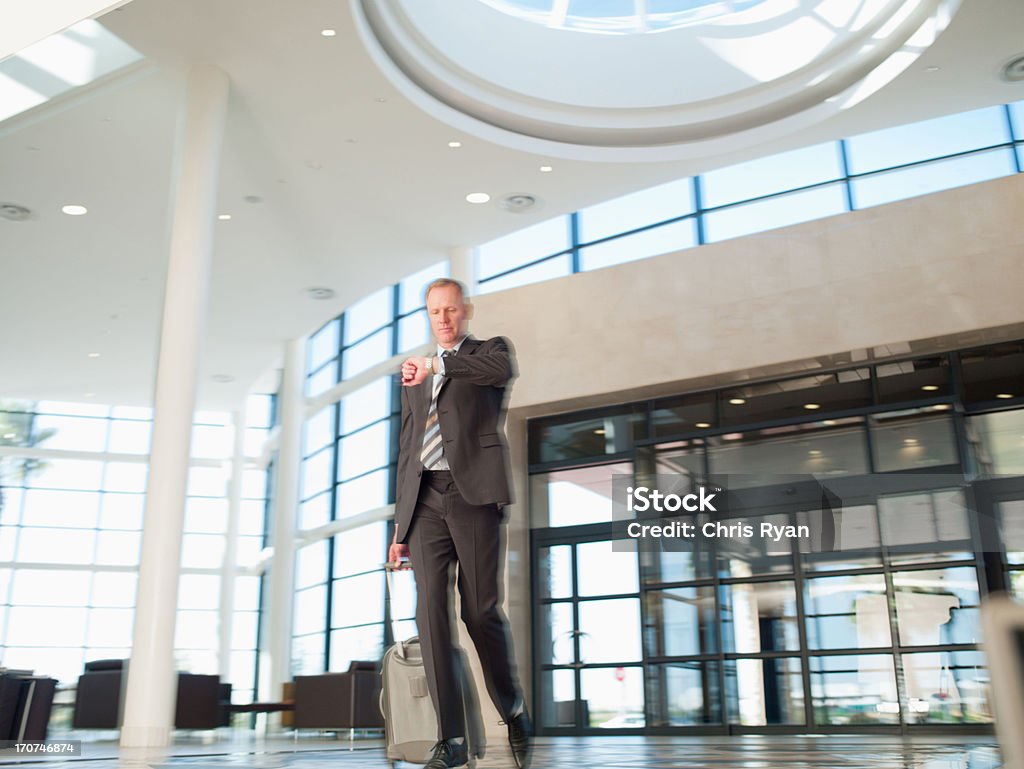 Businessman with luggage checking wristwatch  Businessman Stock Photo