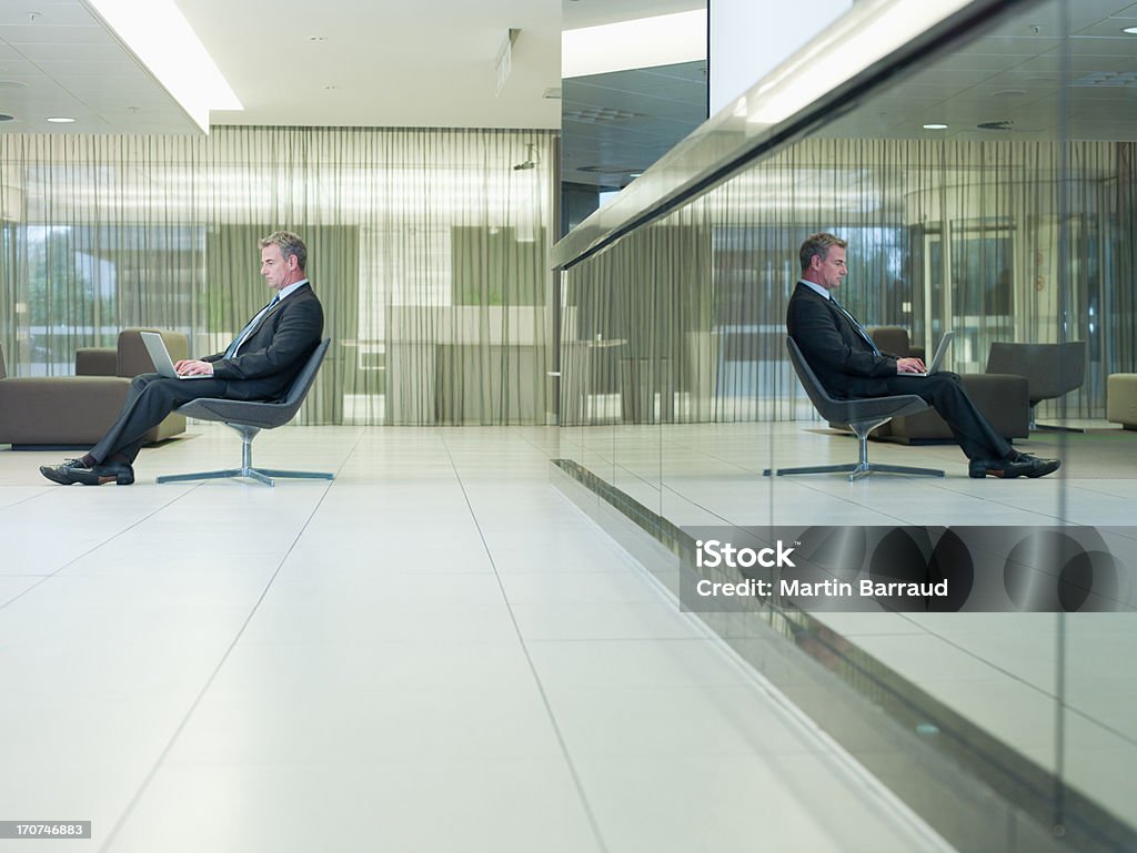 Uomo d'affari digitando sul portatile in ufficio - Foto stock royalty-free di Specchio