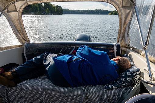 Stockholm, Sweden A senior man sleeps or naps on  bench inside a motor boat.