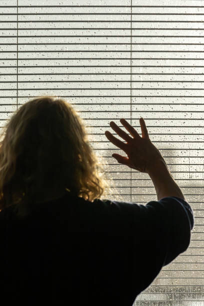 istock A woman looks through blinds 1707483122