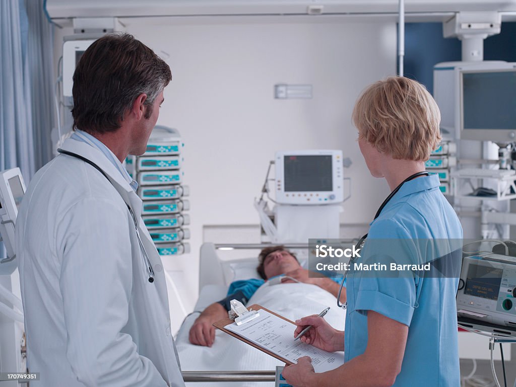 Médico y enfermera hablando en la unidad de cuidados intensivos - Foto de stock de Paciente libre de derechos