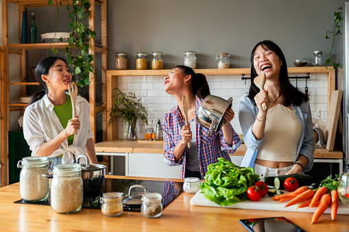 Happy beautiful chinese women friends bonding at home and cooking delicious meal together- Playful pretty asian female adults meeting and having fun at home, concepts about lifestyle, domestic life and friendship