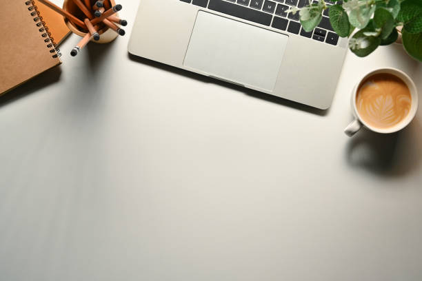 istock Simple workspace with laptop, notepad, coffee cup and potted plant on white table. Top view with copy space for text 1707524127