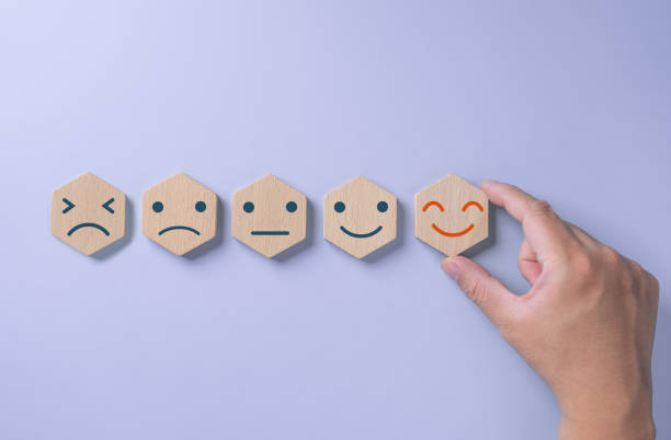 istock Client's hand chooses a smiley happy face icon on a hexagonal wood block. Customer service evaluation and satisfaction survey concept. Positive thinking and excellent feedback on product and service. 1707529805
