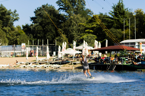 Female wakeboarder wakesurfing. Girl riding waterski cabel. Holding tow rope. Summer activities in the lake.