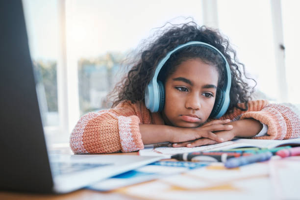 bambino, annoiato e pensante con le cuffie per la scuola a casa, l'e-learning e la futura educazione online. bambino stanco, triste e con adhd, autismo e laptop per disegnare e ascoltare l'audio a tavola - home schooling audio foto e immagini stock