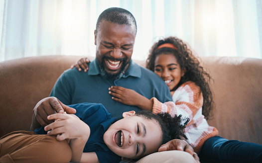 Family, fun and living room with kids, father and love together in a home on a couch. Laughing, young and children with dad and funny joke with bonding, support and care in a house on a lounge sofa