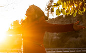 Serene and overjoyed young lady outstretching arms during autumn sunset and hug the planet. People and nature lifestyle. Happiness and freedom. One woman opening arms and smile. Joyful emotion person.