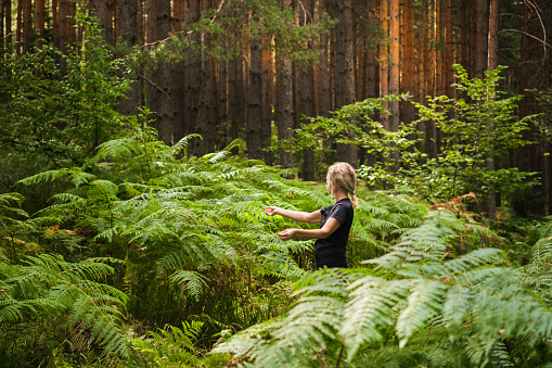 Forest baths, an adult woman in thickets of ferns restoring health and psyche in nature