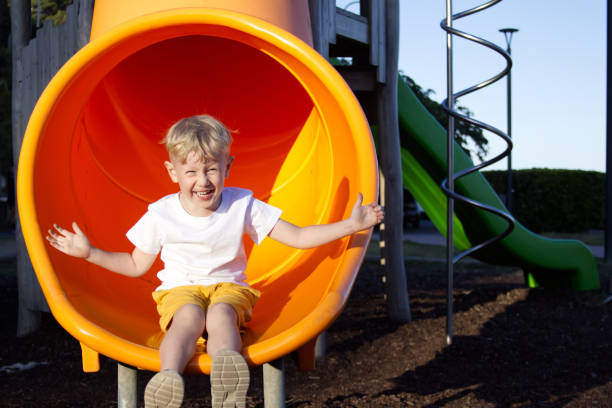 istock A blond boy slides down a slide with his arms outstretched in different directions and smiles on the playground 1707646558