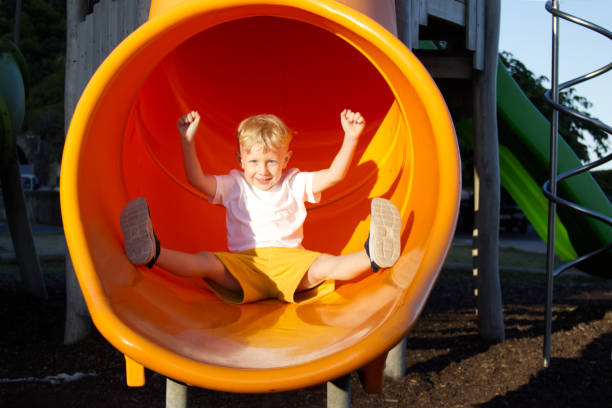 istock A blond boy slides down a slide with his arms outstretched in different directions and smiles on the playground 1707646559