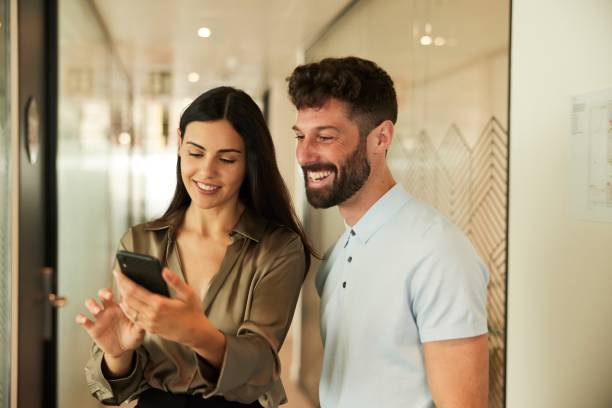 istock Corporate Partners Sharing Information on Smartphone in Office Corridor 1707660199
