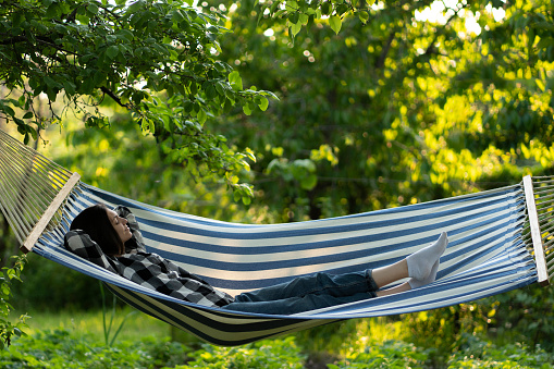 early morning outdoors in the forest, young woman stretching in the hammock