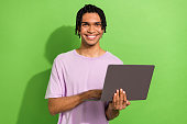 Portrait of positive nice young man beaming smile hold use apple microsoft netbook isolated on green color background