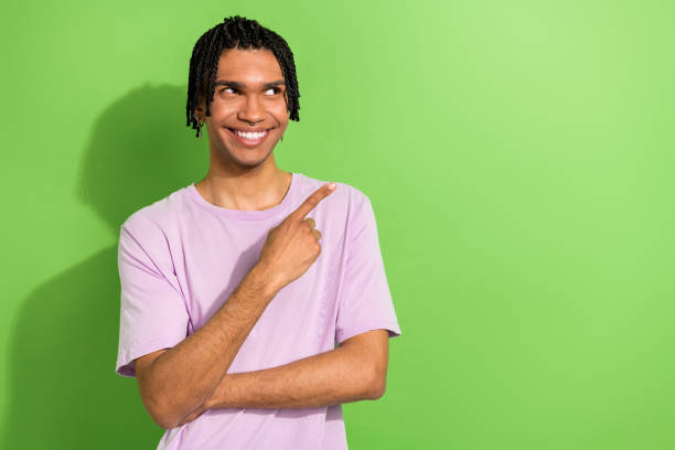 istock Photo of attractive guy looking empty space directing finger ad ads adv wearing oversize shirt isolated green color background 1707713215