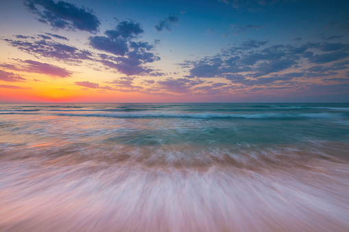 Ocean sunrise over beach shore and waves. The sun is rising up over sea horizon