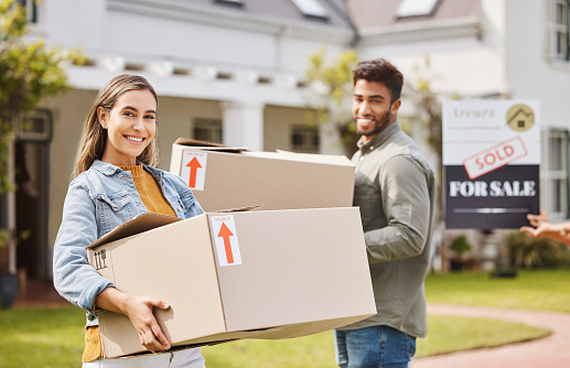 Couple, boxes and portrait for new home, real estate and property, homeowner and outdoor neighborhood. Young and happy interracial people with cardboard, moving in dream house together and sold sign