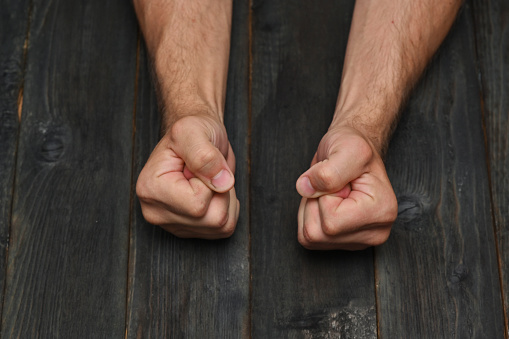 fists of a man on a dark wooden table.
