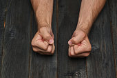 fists of a man on a dark wooden table. Close-up. Concept