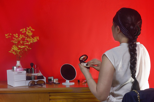 Woman Doting Make-Up on the Red Background//Studio Shot