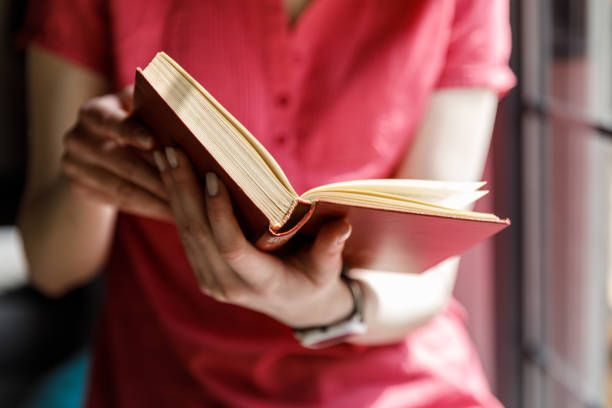 istock Young woman sitting by the window, enjoying reading a book 1707783891