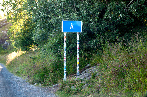 A, Norway - July 20, 2015: A roadside road sign marking the fishing village of A in the Lofoten Islands, Norway. Iron road sign with stands covered with stickers.