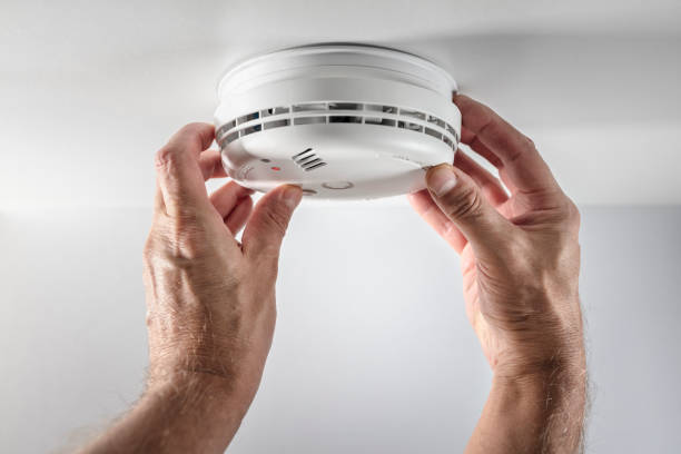 Home smoke and fire alarm detector installing, checking, testing or replace battery stock photo