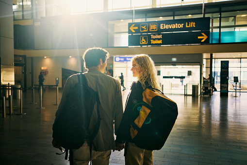 Young adult couple at the airport, looking for their departure gate, heading away on a weekend vacation.