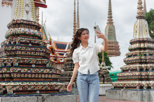 Asian young woman tourists are selfie photos with a smartphone at the Wat Pho temple on vacation Bangkok Thailand.