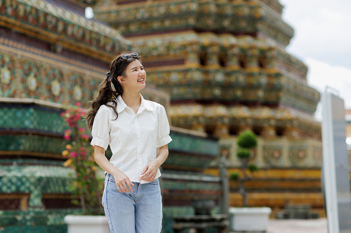 Asian woman walk around and look big pagoda at Wat Pho temple in Bangkok Thailand